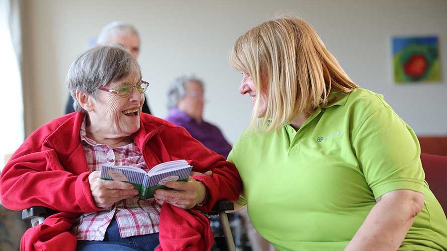 Eine Mitarbeiterin der AllgäuPflege und eine Frau schauen sich gegenseitig lächelnd in die Augen